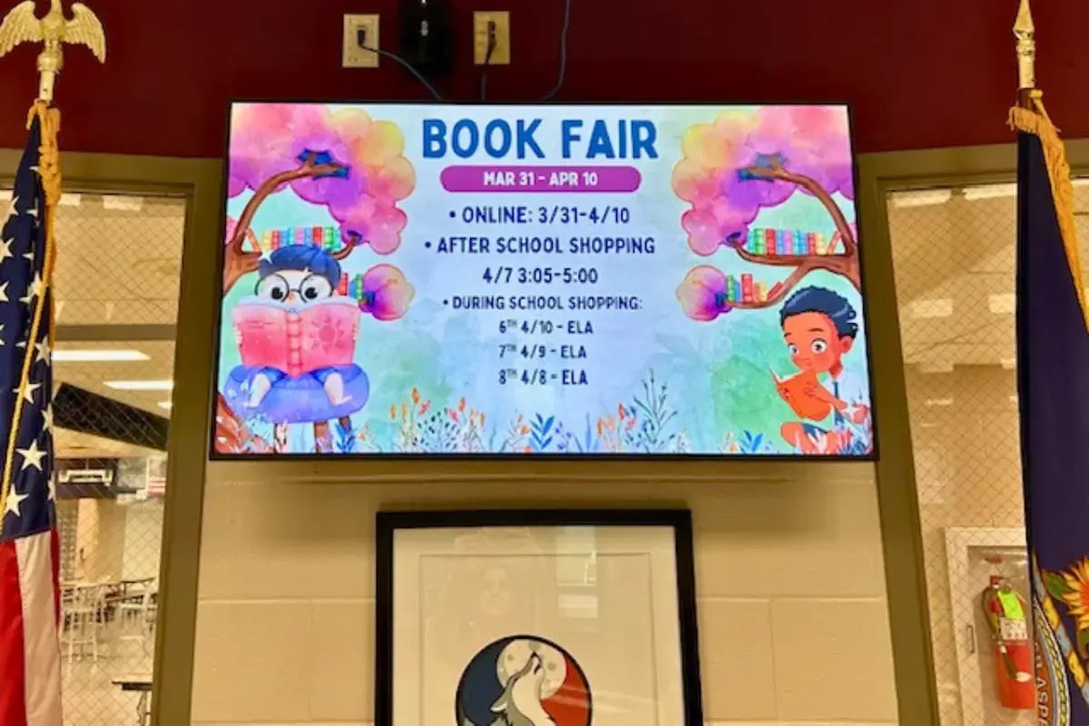 A large display showing a Book Fair template mounted to the wall of a school hallway