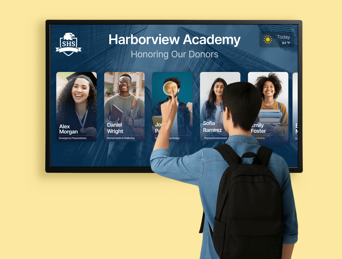 A male university student tapping on an interactive donor wall display