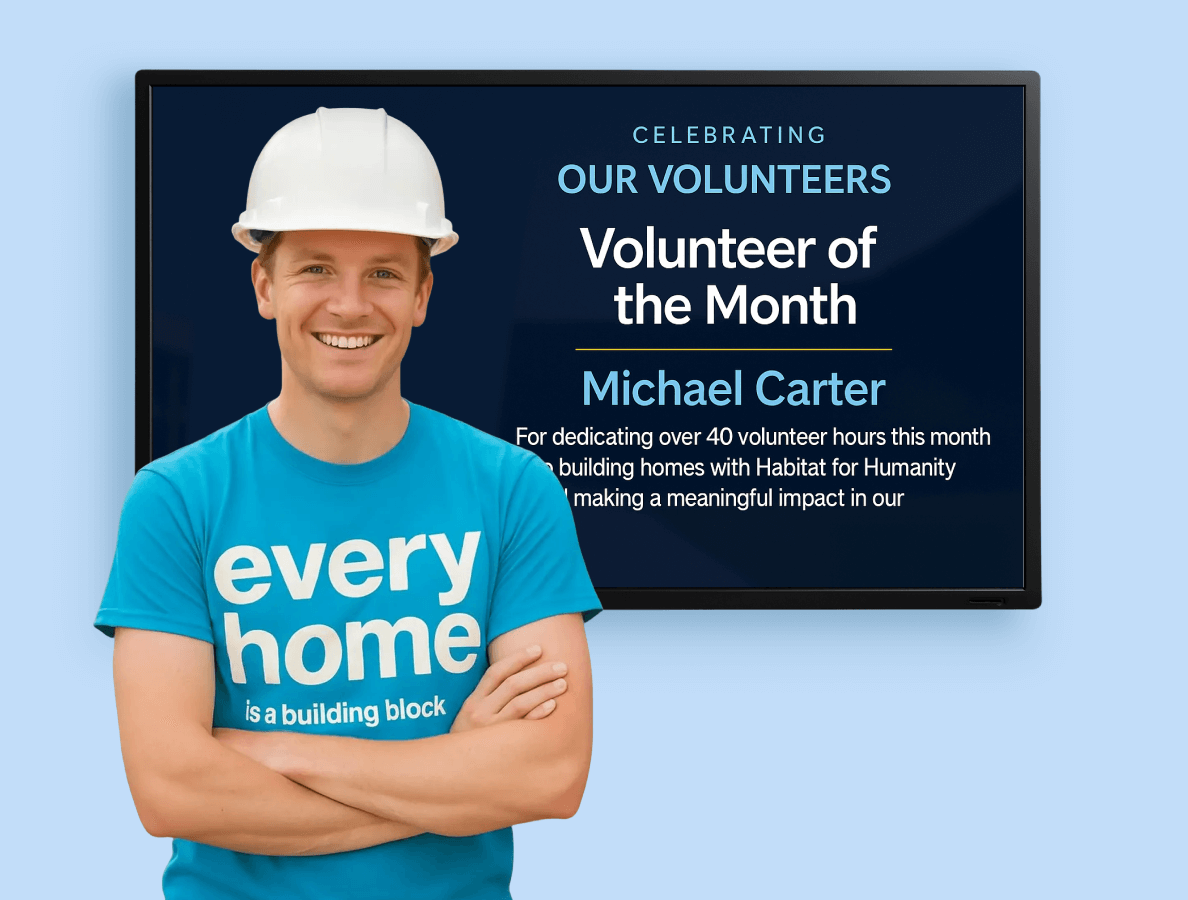 A worker standing in front of a digital display celebrating volunteer of the month