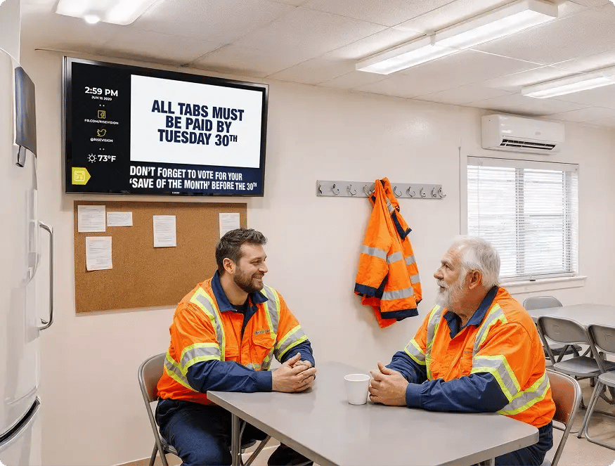 A digital information board mounted on a wall inside a cafeteria for logistics employees