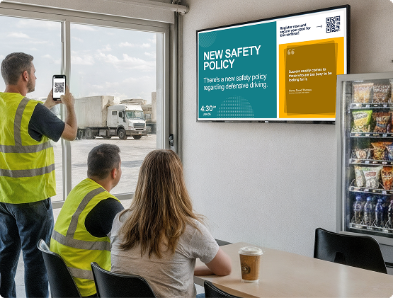 Three transportation and logistics employees sitting at a coffee table and viewing safety policy on a digital signage display