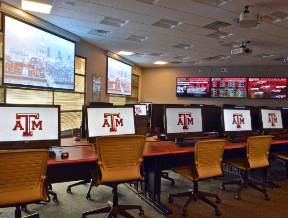A large lab with computers, overhead displays and large mounted TVs with financial charts