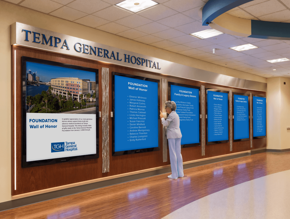 An elderly woman looking at a hospital philanthropy display in a hospital