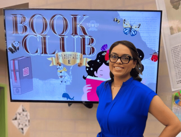A female student standing in front of a Book Club digital signage display