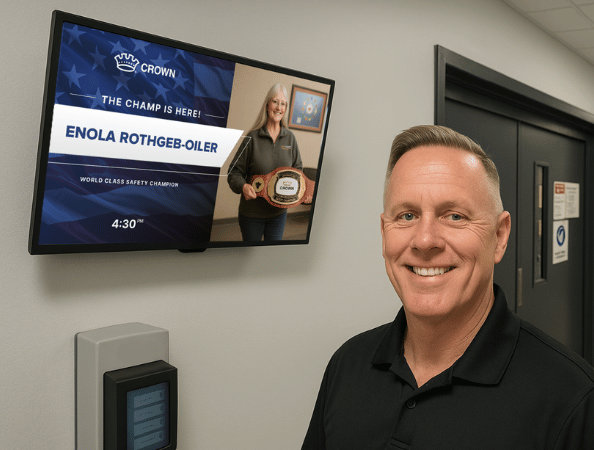 A male standing next to a digital display about an Employee Spotlight
