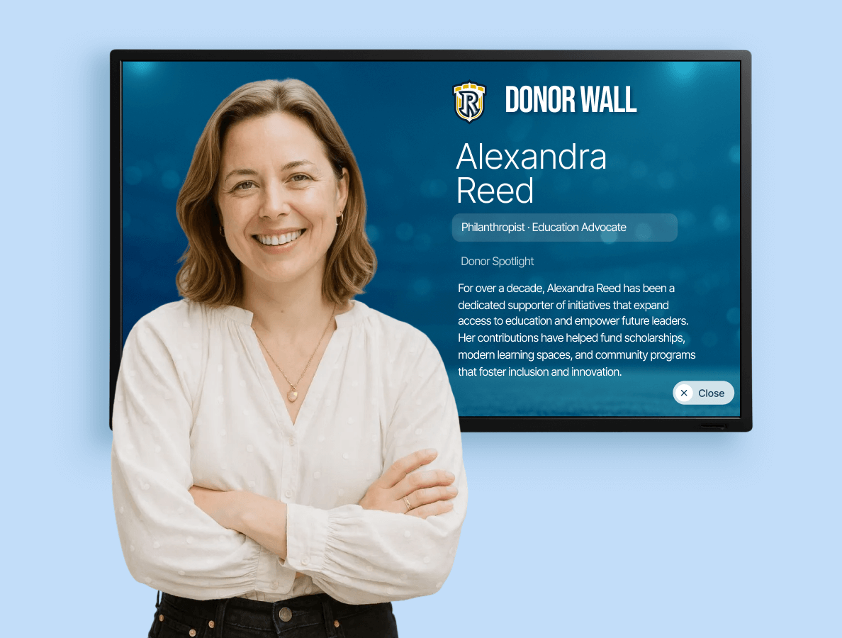 A woman standing in front of a donor wall display