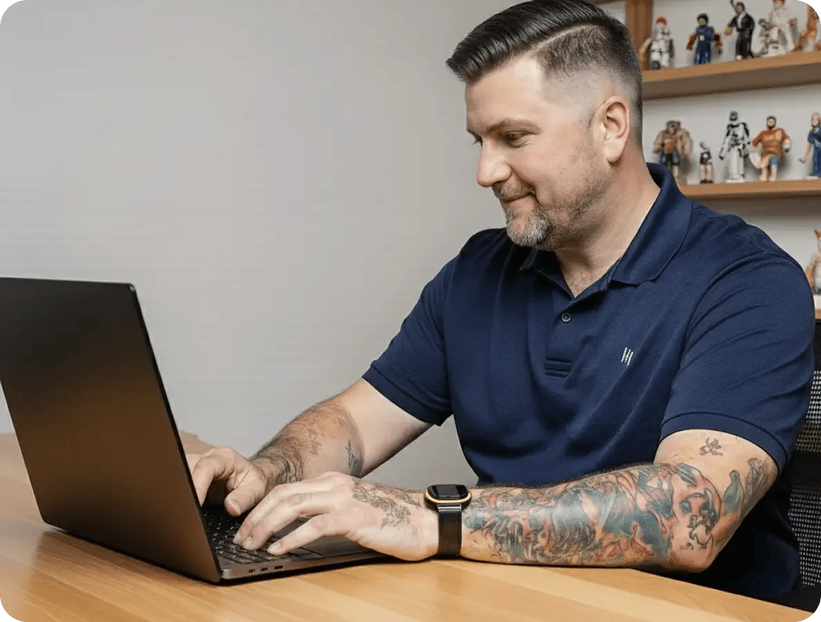 A male sitting at a desk using a laptop