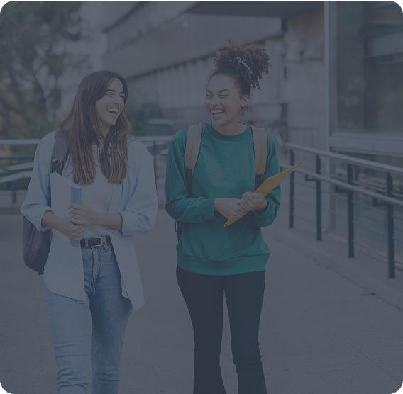 Two female college students walking and laughing on campus walkways