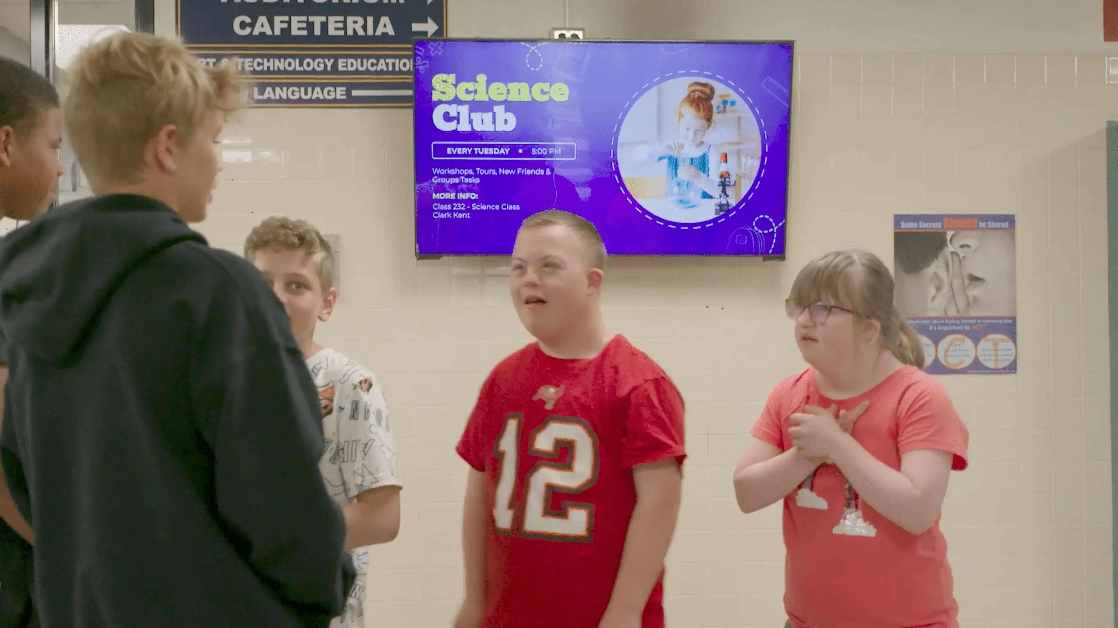 Students standing in a hallway with digital signage