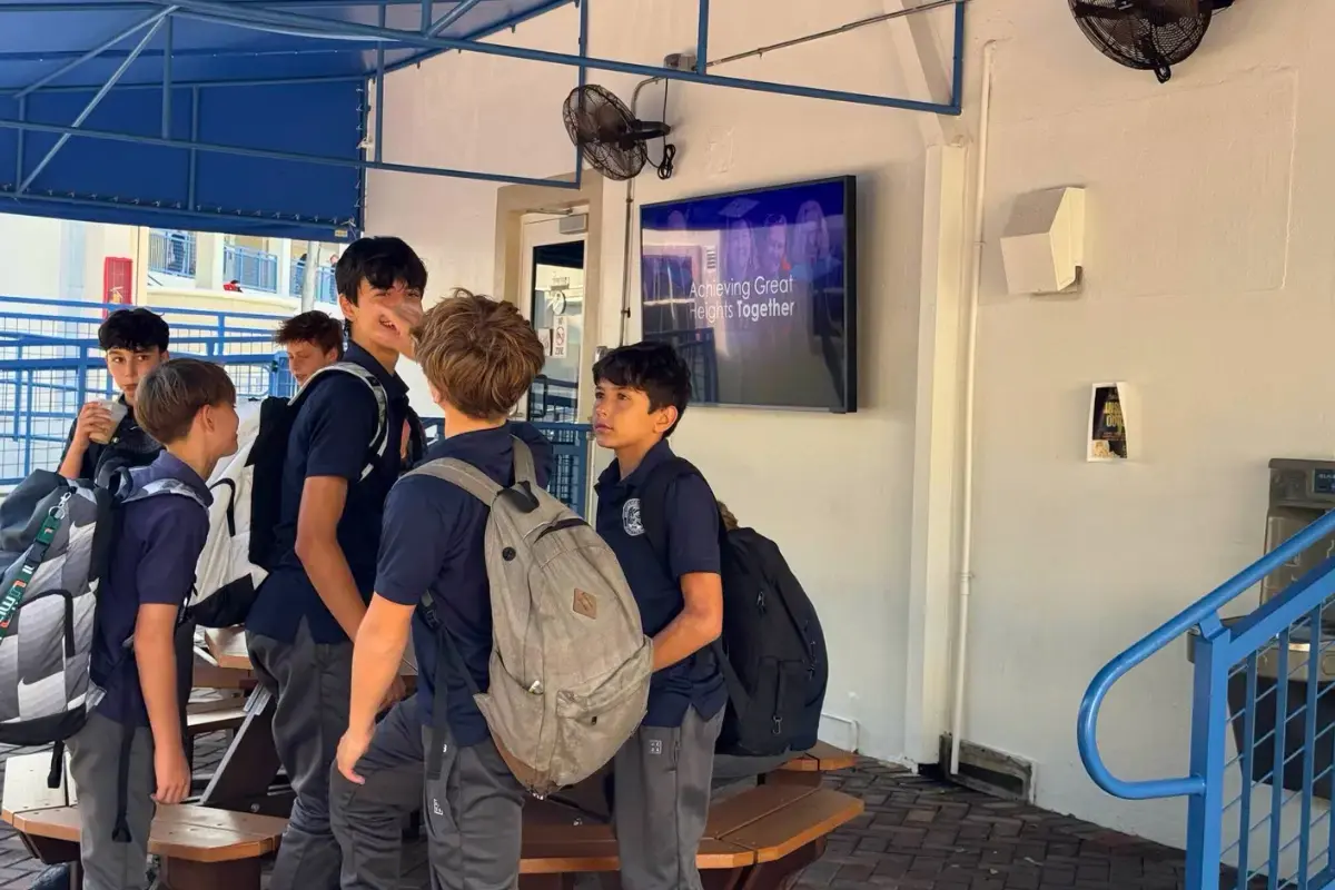 Young students crowding together with a digital signage display