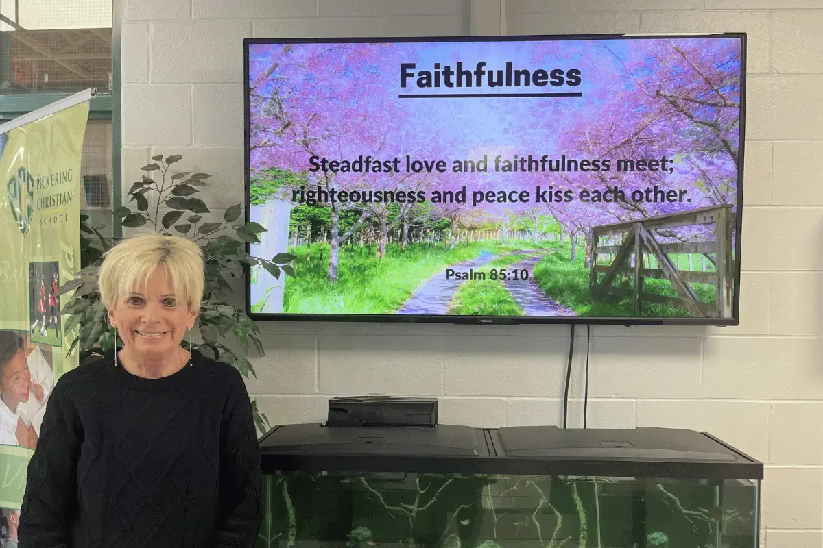 A female standing next to a digital display