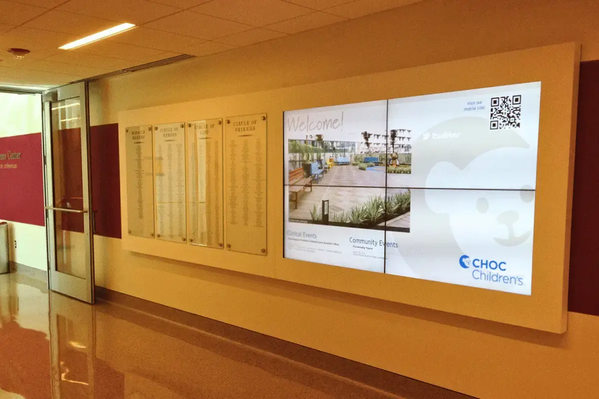 A multi digital display mounted on the wall of a ward in a hospital
